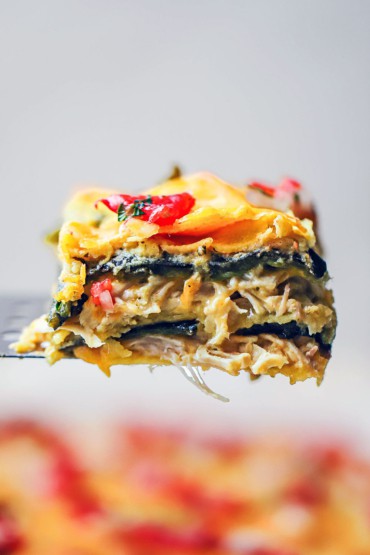 A square slice of a green enchilada casserole being raised up on a metal spatula.