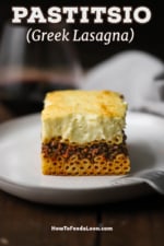 A straight-on view of a perfectly square piece of Greek pastitsio on a white dinner plate.