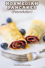 A close-up view a rolled Norwegian pancake the has been filled with blueberry jam and then cut in half so the insides are revealed.