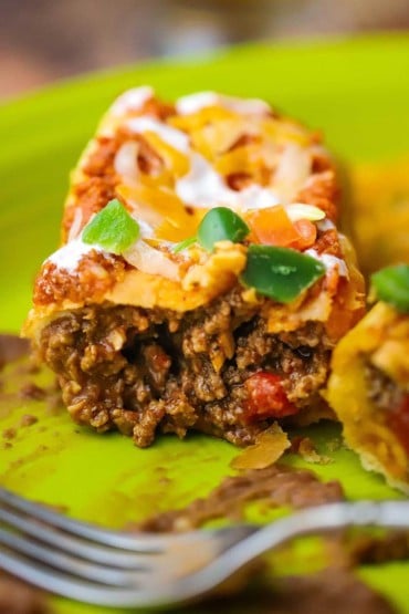A close-up view of a juicy ground beef chimichanga on a plate and it has been split open to review the meaty insides.