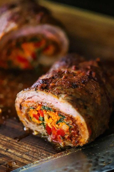 A close-up view of a sliced roasted rolled flank steak that has been stuffed with carrots, peppers, and herbs.