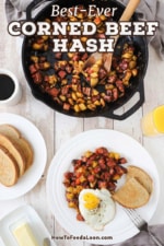 An overhead view of a white plate filled with a serving of corned beef hash with a fried egg on top and two slices of rye bread next to it as well as a skillet of the hash near the plate of food.