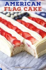 A close-up view of an American Flag Cake that has a piece cut from the corner to reveal the white cake interior.