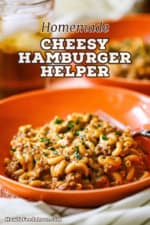 A close-up view of an orange dinner bowl filled with a serving of homemade cheesy hamburger helper.