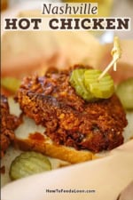 A close-up view of a piece of Nashville hot chicken sitting on a slice of white bread with two dill pickle slices attached to the chicken with a toothpick.