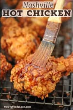 A person using a small brush to apply Nashville hot oil to a piece of Nashville fried chicken which is crispy leg on a baking rack.
