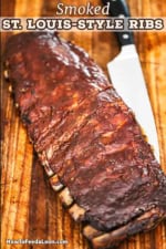A straight-on view of a rack of smoked St. Louis-style ribs resting on a wooden cutting board with a large sharp knife next to it.