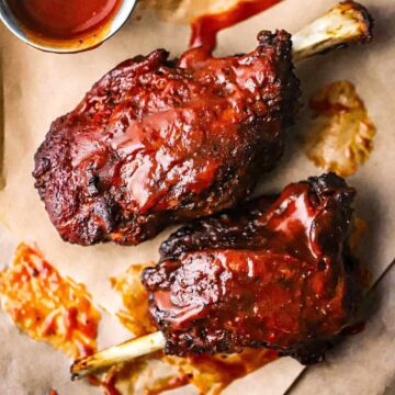 An overhead view of two smoked pork wings that are fully cooked and slathered with homemade barbecue sauce.