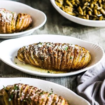 Several hasselback potatoes resting in individual baking dishes.