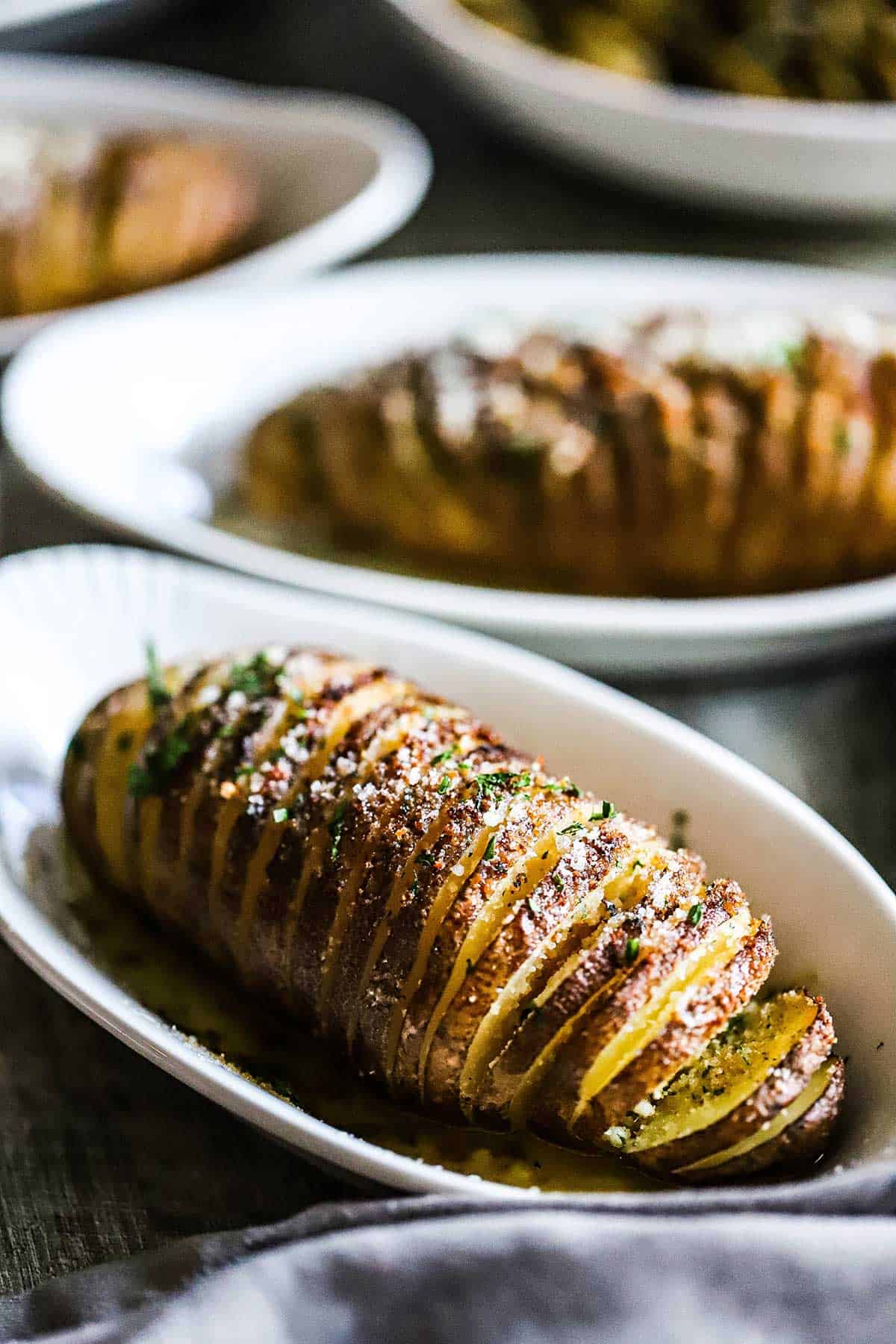 Several hasselback potatoes resting in individual baking dishes. 