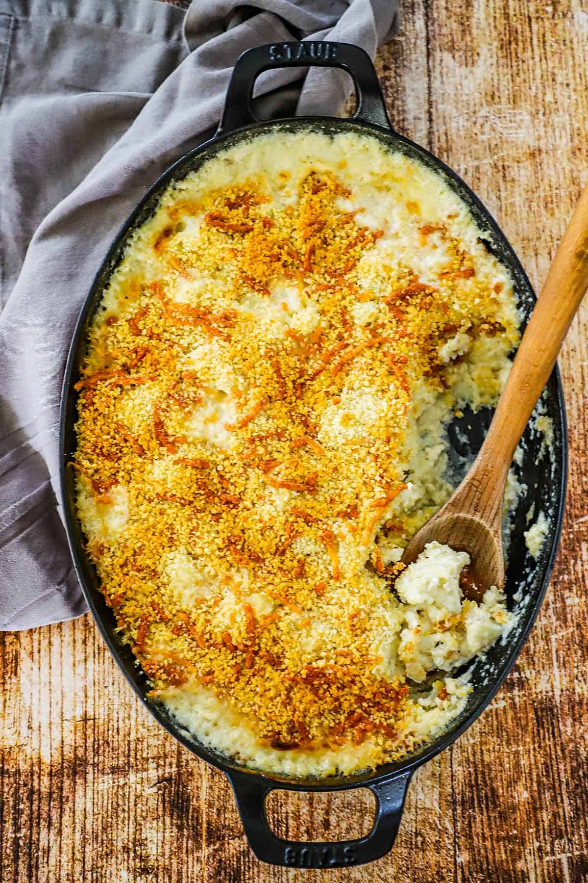 Creamy cauliflower gratin in an oval baking dish with some of it gone. 