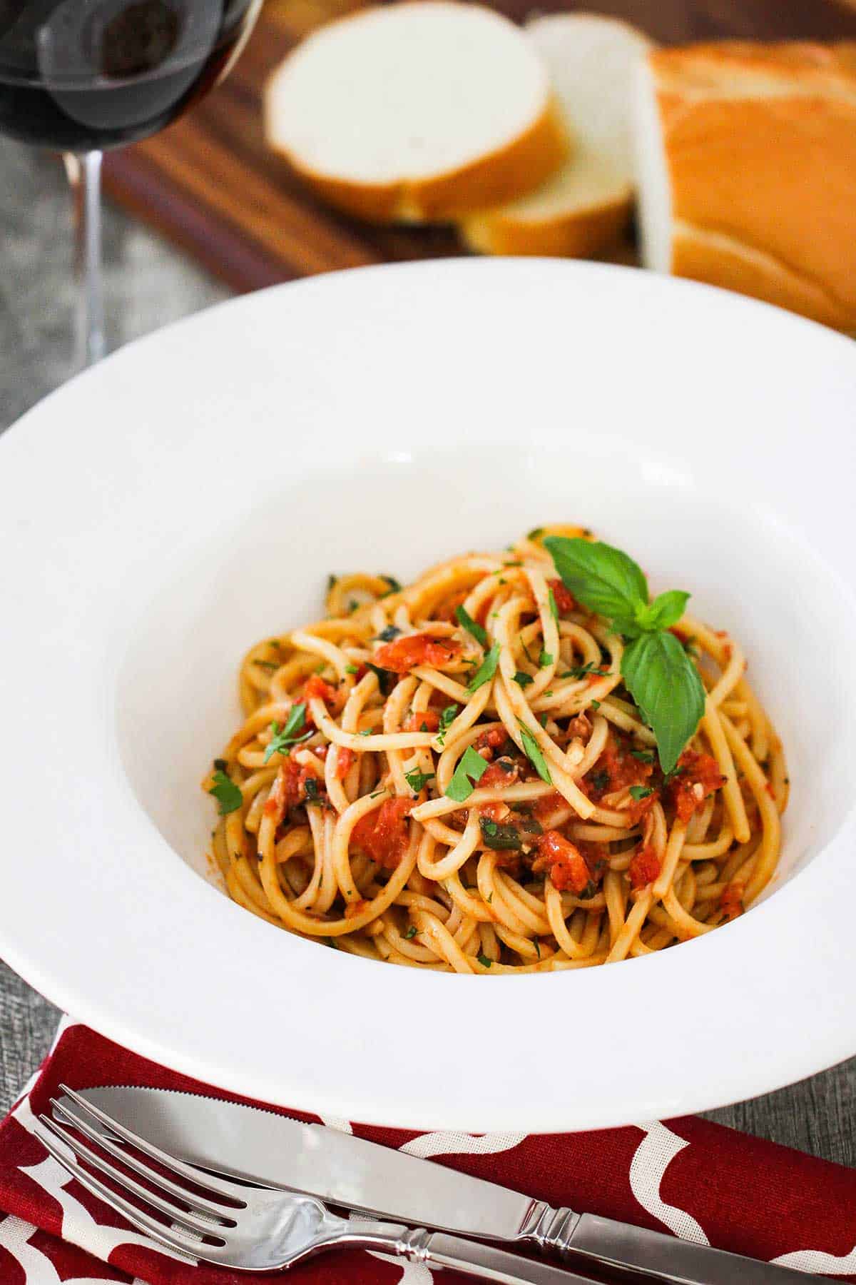 A white pasta bowl with a wide lip is filled with a serving of pasta pomodoro. 