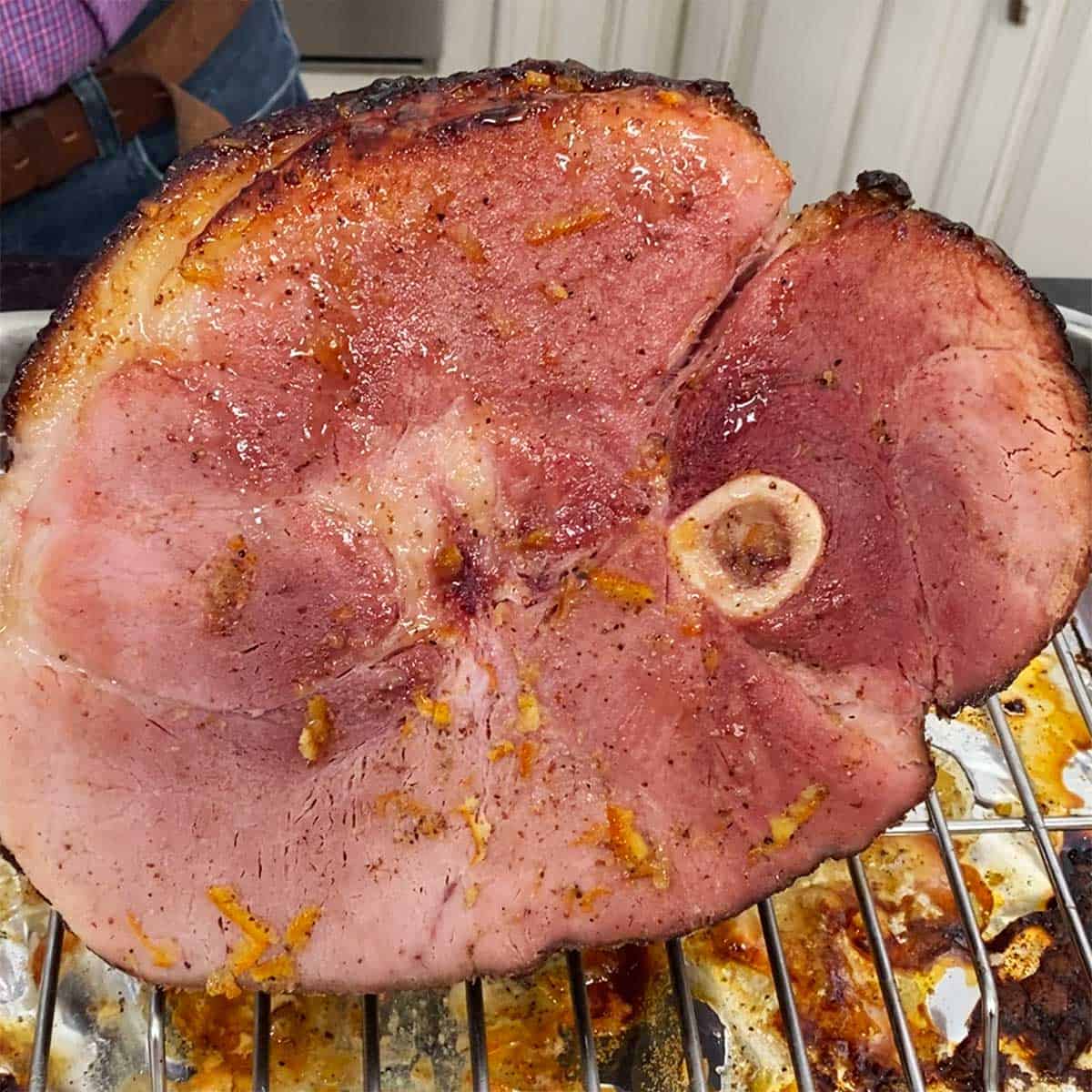 A holiday ham that has been baked with a glaze on it resting in the roasting pan. 