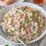 A white serving bowl filled with best-ever ham salad with a large spoon inserted off to the side.