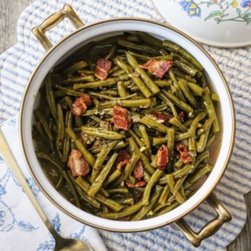 A round pot filled with Southern-style green beans on a white and blue striped place setting.