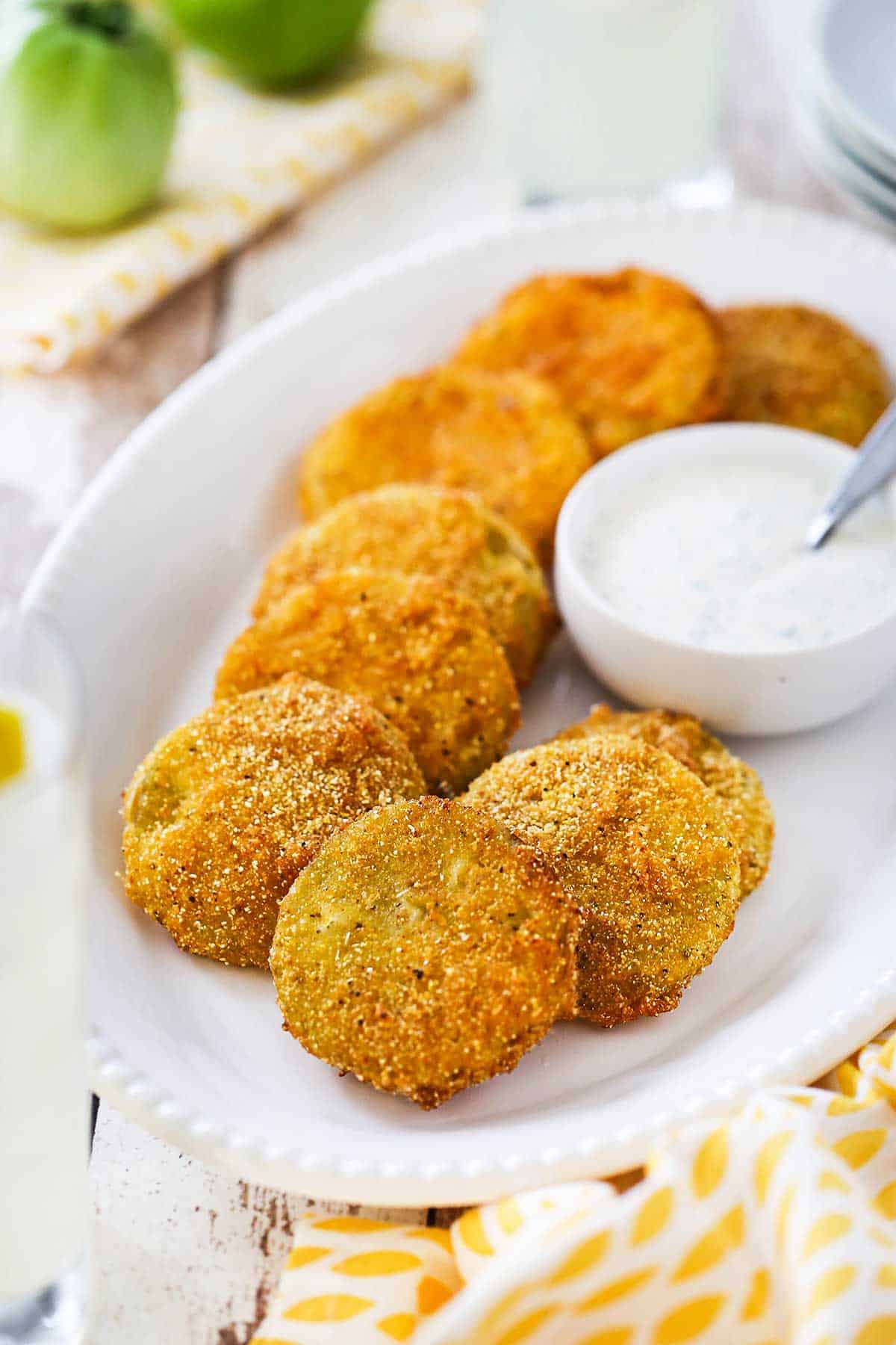 A platter filled with freshly made classic fried green tomatoes with a bowl of Ranch dressing sitting next to them.