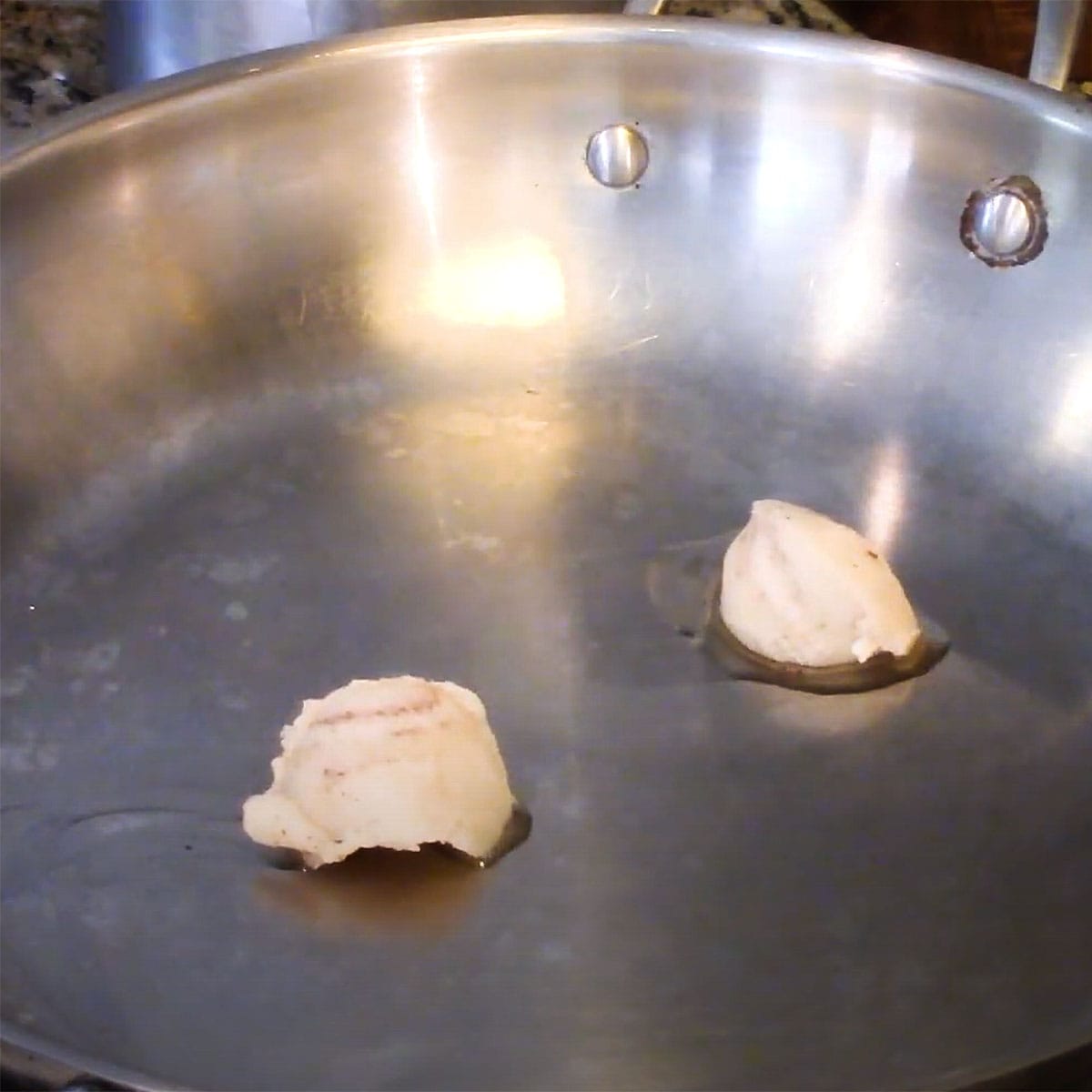 Two small balls of bacon grease in a large skillet just starting to melt over medium heat.