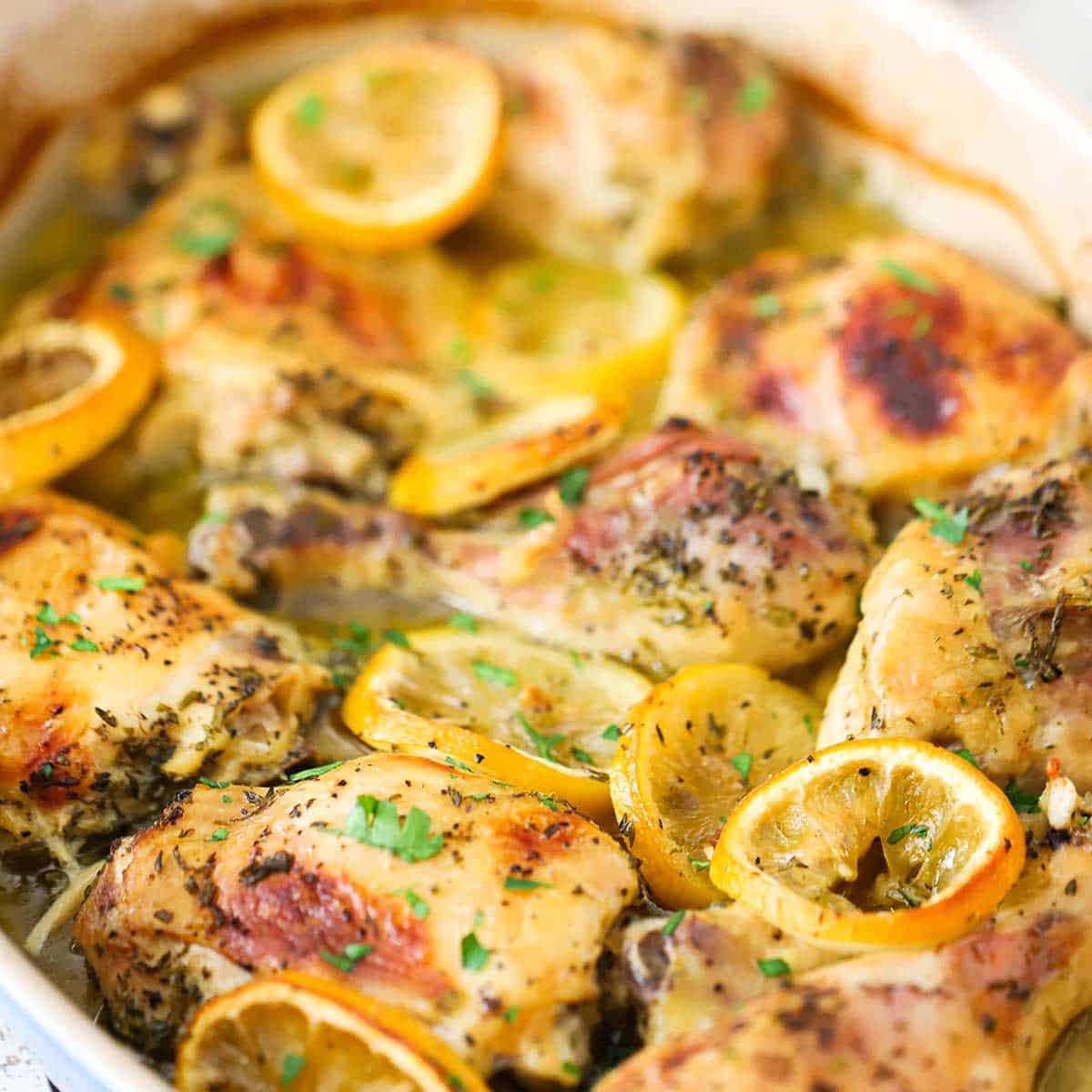 Chicken pieces that have been roasted and browned with lemon slices, herbs, oil, and white wine.