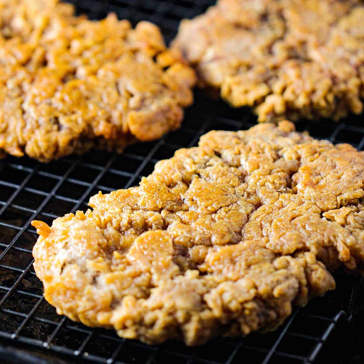 Crispy Southern fried steak cutlets resting on a baking rack on a baking sheet. 
