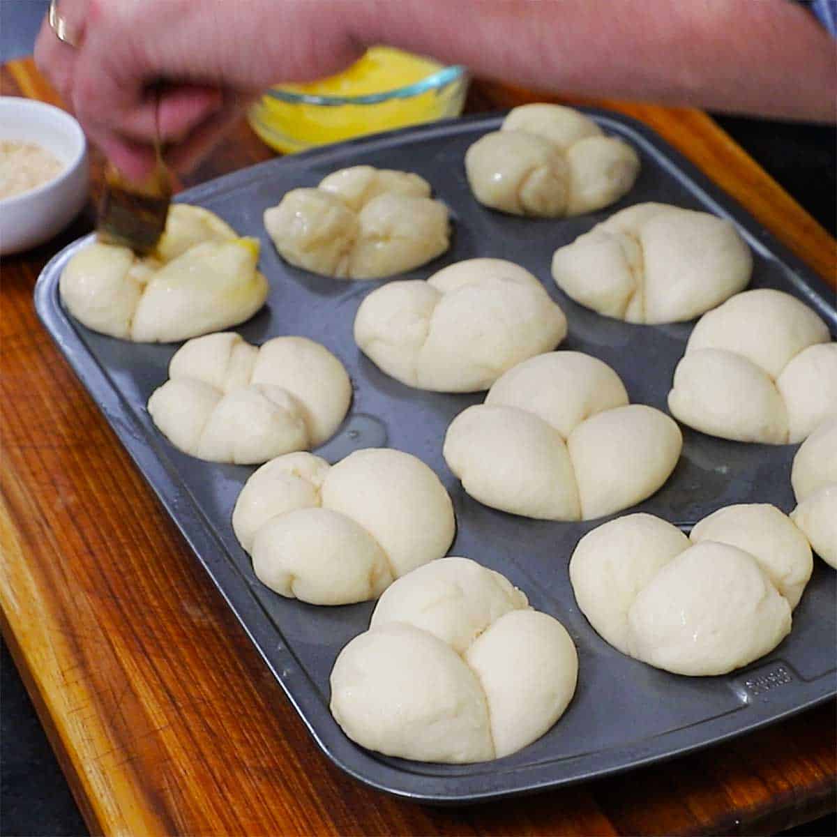 A muffin pan that is filled with risen uncooked dough triangles. 