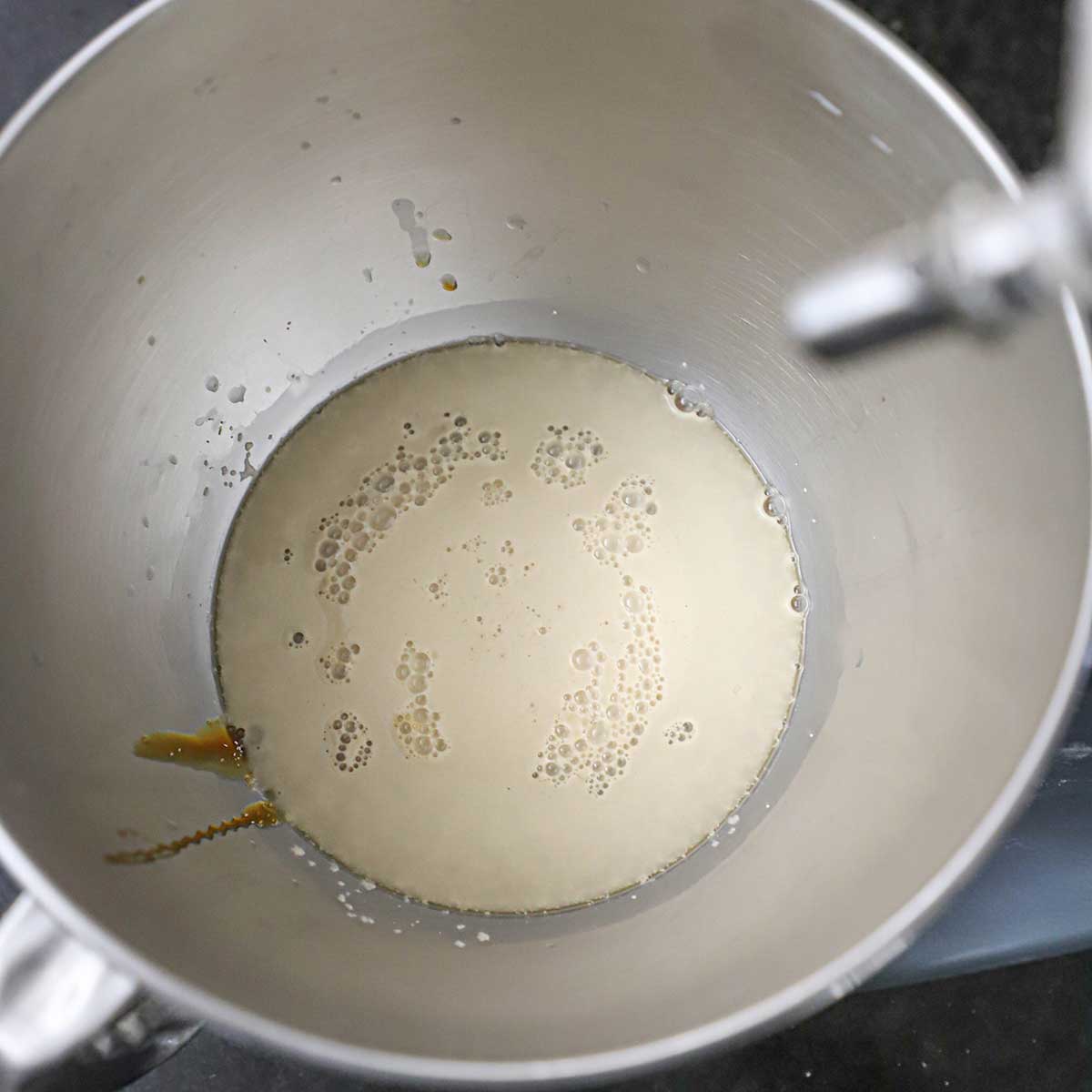 Yeast that is foamy in a mixer bowl filled with warm water and malt barley syrup.