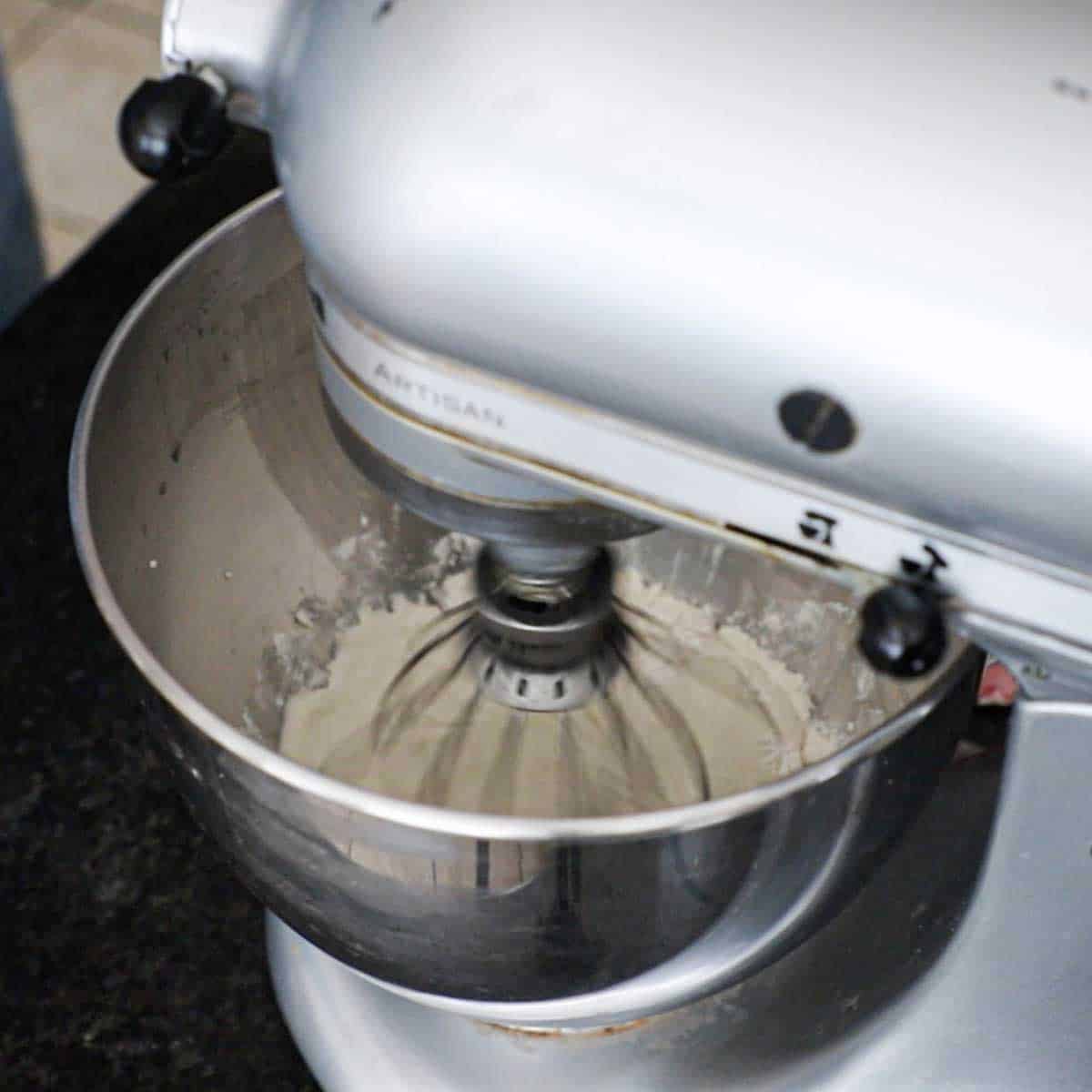 A stand-mixer mixing flour into a dough sponge with the whisk attachment.