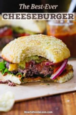 A best-ever cheeseburger with homemade buns and all the toppings sitting on a brown piece of paper with a bite missing from it.