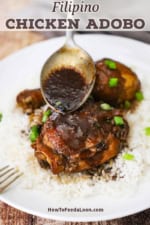 A person spooning a dark brown sauce of the top of a serving of Filipino chicken adobo.