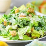 A close-up view of a classic Caesar salad topped with homemade croutons and grated Parmesan cheese.