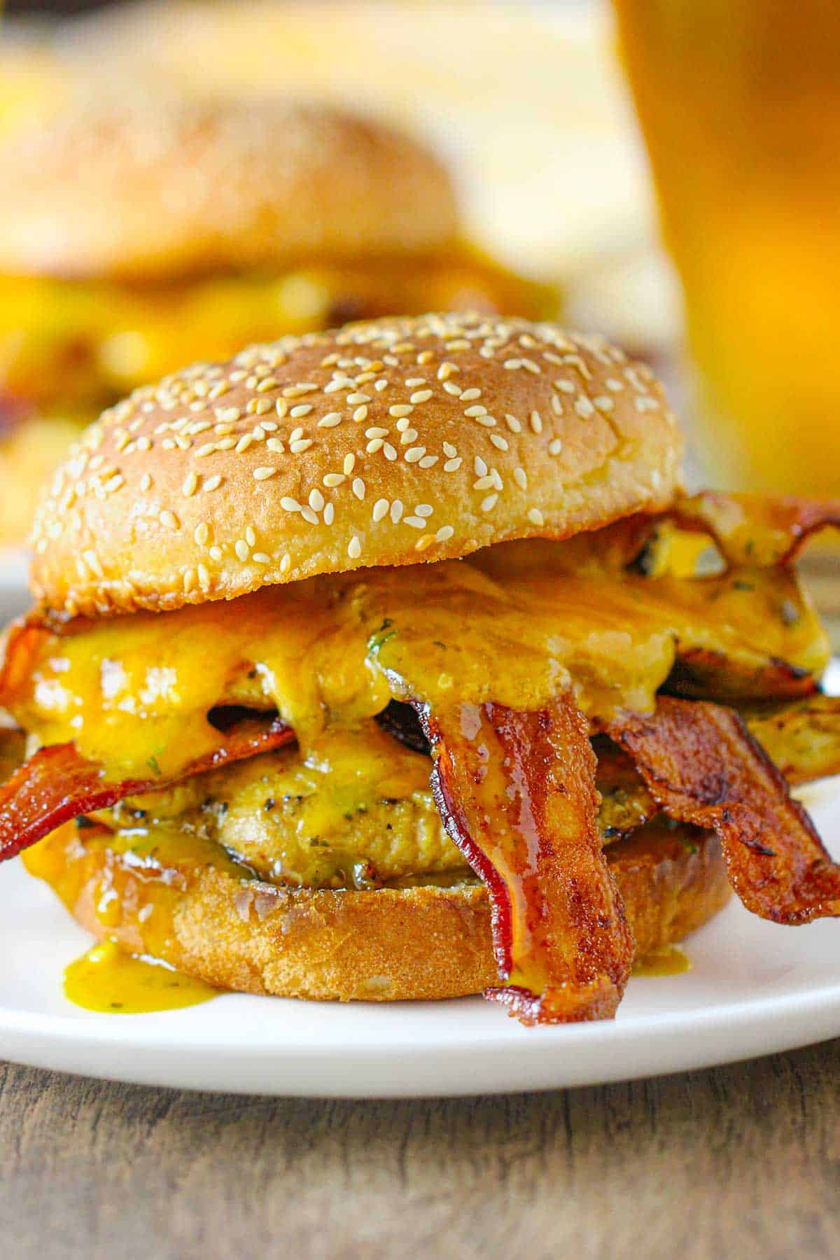 A grilled honey mustard sandwich consisting of two pieces of chicken, melty cheddar cheese, and multiple strips of crispy bacon on a toasted sesame bun.