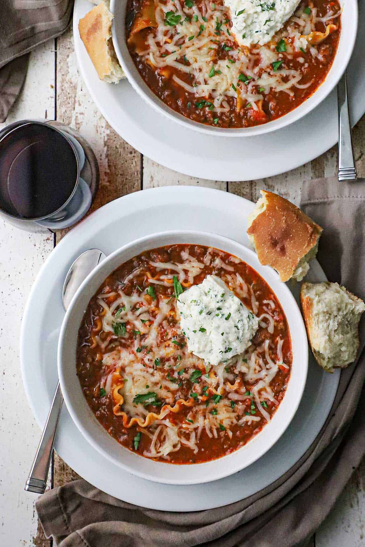 An overhead view of two side-by-side bowls both filled with a serving of slow cooker lasagna soup.