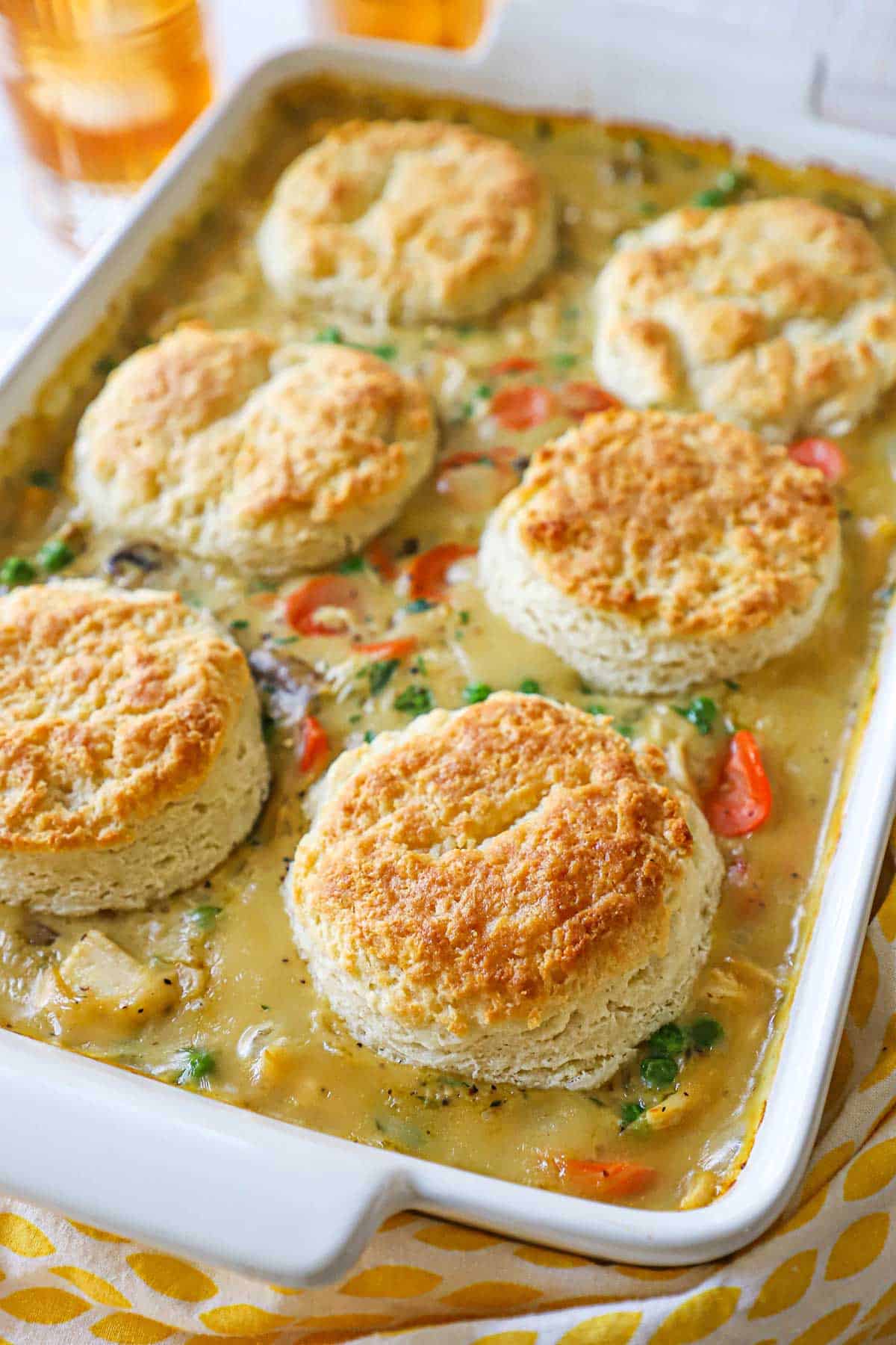 A white casserole dish filled with a freshly baked chicken and biscuits casserole.