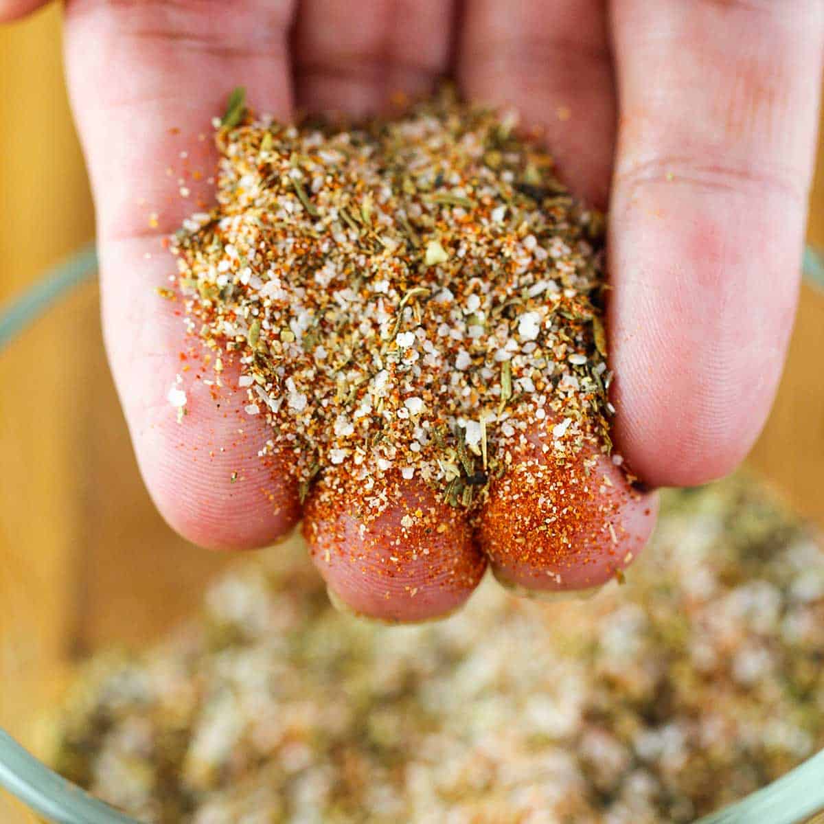 A person holding blackening seasoning in his hand over a bowl of the same.