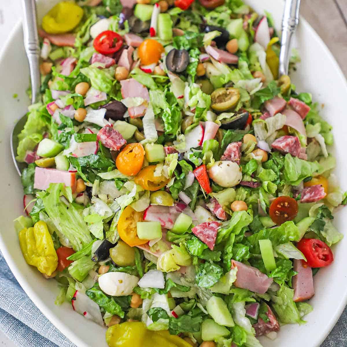 An overhead view of an Italian chopped salad with homemade vinaigrette on a large platter being served family-style.