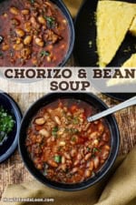 An overhead view of two dark blue soup bowls filled with servings of chorizo and bean soup with a plate filled with cornbread triangles nearby.