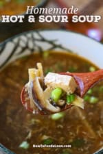 A person holding a wooden spoon filled with homemade Chinese hot and sour soup over a bowl of the same.