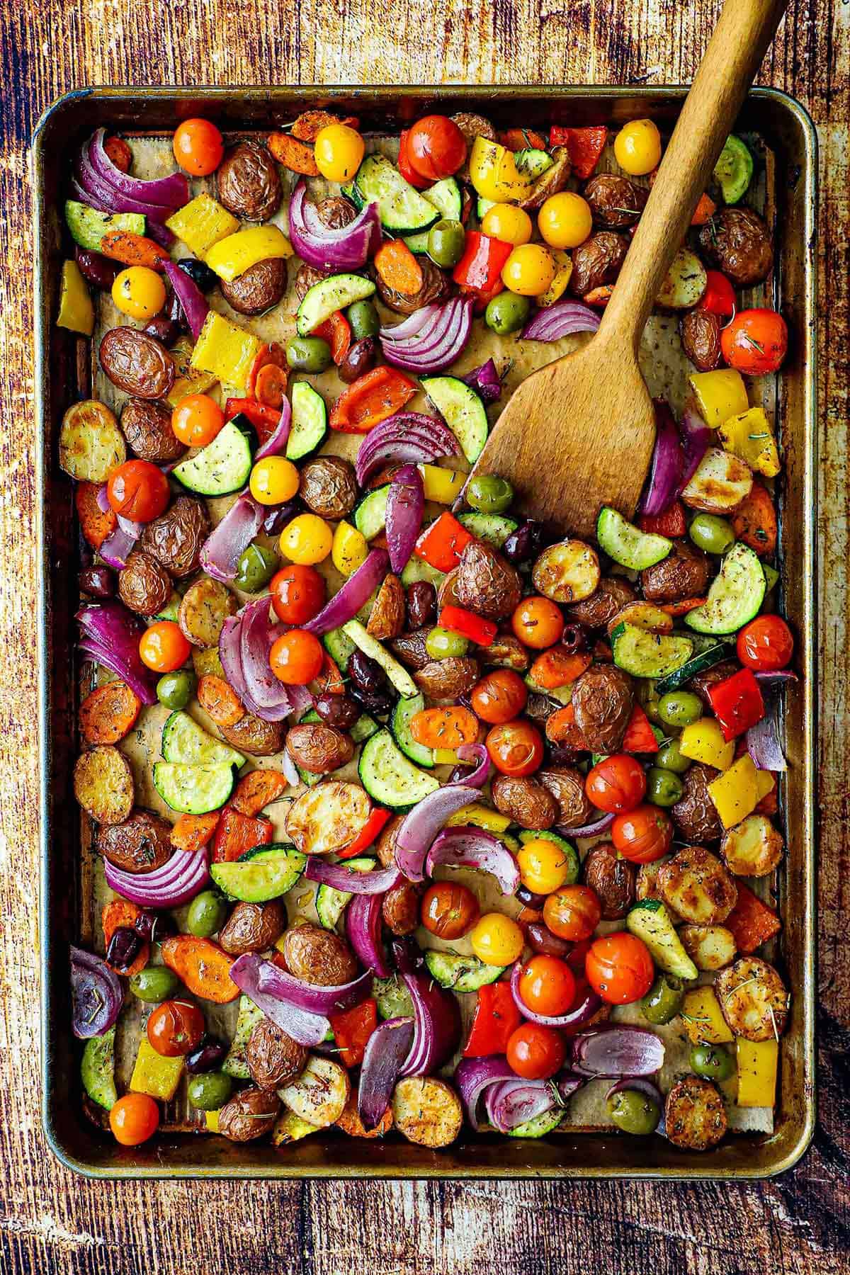 An overhead view of a large baking pan filled with a colorful medley of Mediterranean roasted vegetables.