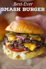 A person holding a double-stacked best-ever smash burger in his hand.