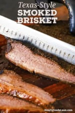 A person using a large brisket knife to slice into a partially sliced, fully cooked beef brisket flat on a cutting board.