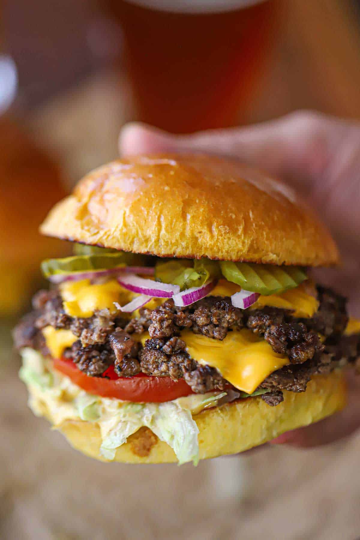 A person holding a double-stacked best-ever smash burger in his hand.