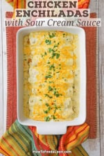 An overhead view of a white casserole filled with freshly baked chicken enchiladas with sour cream sauce.