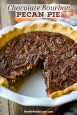 A chocolate bourbon pecan pie in a white pie dish with a slice missing.
