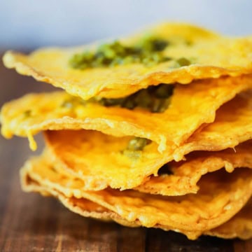 A close-up view of a stack of classic nachos topped with chopped jalapeños.