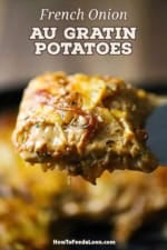 A person using a large metal spatula to raise up a square piece of French onion au gratin potatoes over a skillet filled with the same.