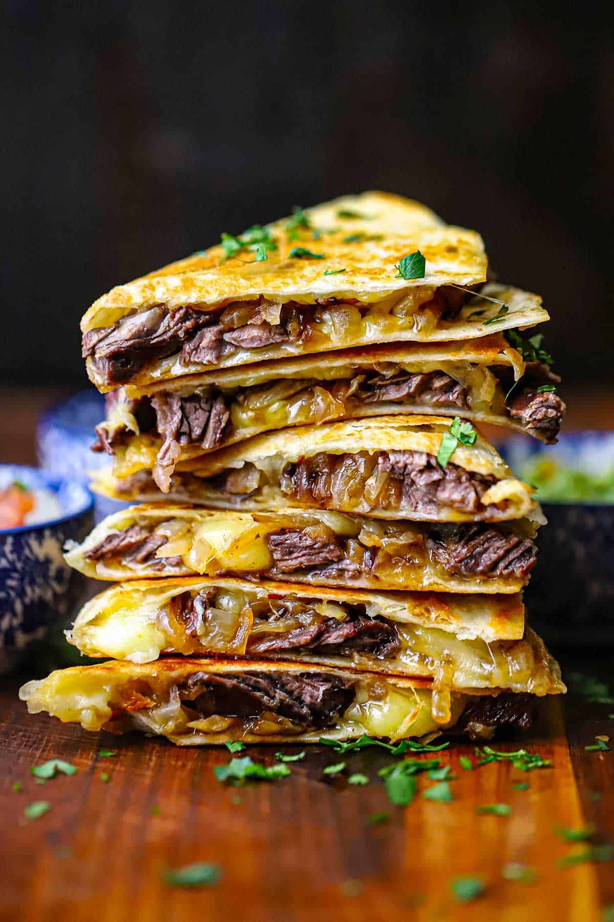 A stack of six steak fajita quesadillas that have been cut in half, revealing the steak, caramelized onions, and melty Monterey Jack cheese.