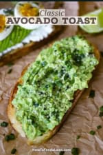 A close-up view of a classic avocado toast with freshly smashed avocado spread onto a toasted slice of sourdough bread and topped with seasonings and snipped chives.