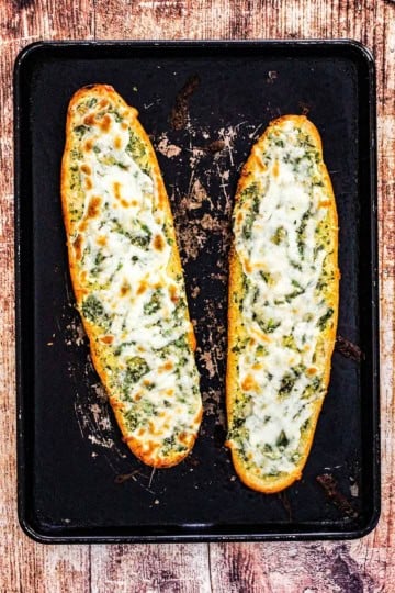 An overhead view of two freshly baked loaves of cheesy garlic bread.