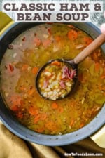 An overhead view of a large stock pot filled with Classic Ham and Navy Bean Soup with a wooden ladle inserted in the middle of it lifting a serving of it.