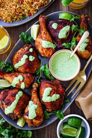 An overhead view of Authentic Roasted Peruvian Chicken with chicken pieces topped with a drizzle of green sauce (aji verde).