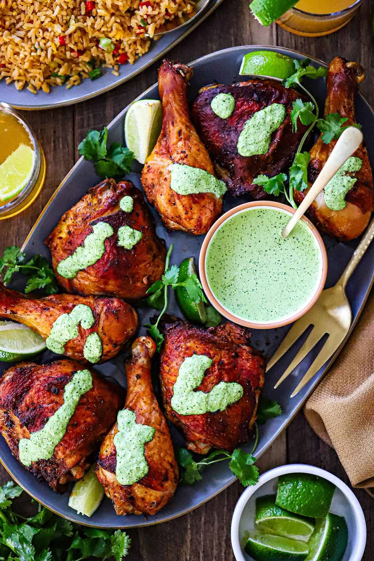 An overhead view of Authentic Roasted Peruvian Chicken with chicken pieces topped with a drizzle of green sauce (aji verde).